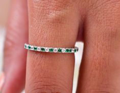 a woman's hand with a diamond and emerald band