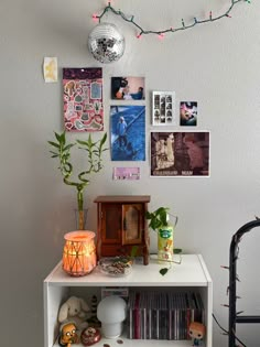 a white shelf topped with lots of books next to a wall covered in pictures and plants