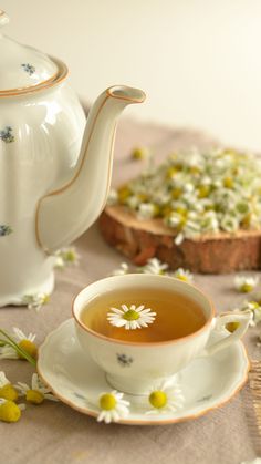 a tea cup and saucer sitting on a table with flowers in the foreground