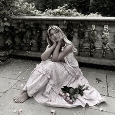 a woman sitting on the ground next to flowers