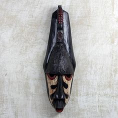 an african mask hanging on the wall in front of a white background with black and red accents