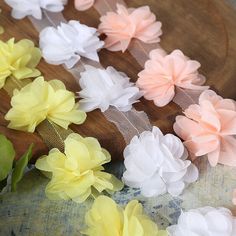 several different colored flowers sitting on top of a wooden board