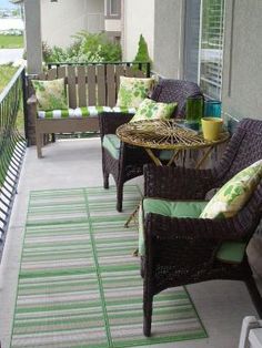 a balcony with wicker furniture and green striped rugs on the front porch area