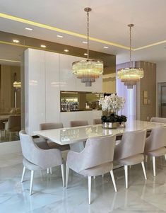 a dining room table and chairs with chandeliers