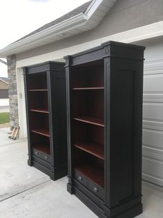 two black bookcases sitting in front of a garage