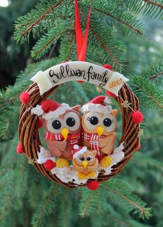 an ornament hanging from a christmas tree with two owls in the middle and one owl wearing a santa hat