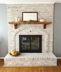 a white brick fireplace with candles and pumpkins on the mantel in front of it