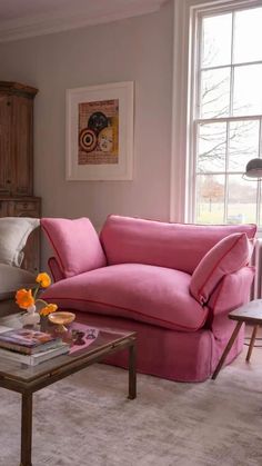 a living room filled with furniture and a pink couch in front of a large window