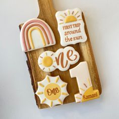 decorated cookies are arranged on a wooden cutting board with the words first thing around the sun