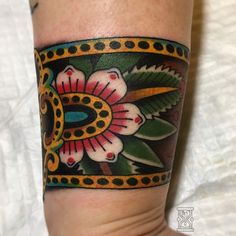 a colorful flower tattoo on the left arm and leg, with an ornate border around it