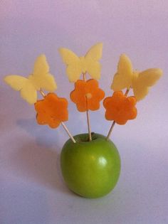 a green vase filled with orange and yellow butterflies