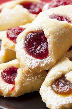 small pastries are piled on top of each other with powdered sugar and jelly toppings