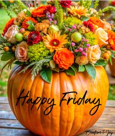 a pumpkin filled with flowers sitting on top of a wooden table