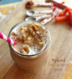 a smoothie is sitting on a cutting board next to carrots