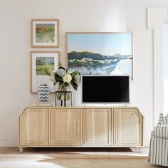 a living room with a television and pictures on the wall above it's entertainment center