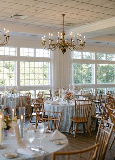 The image shows the reception space at the Coonamesset in Falmouth, Cape Cod. The image shows the tables set up with light blue patterned linens and colorful flower centerpieces. Cape Cod