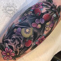 a woman's arm with a bat and flowers on it