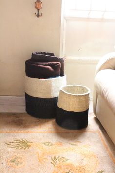 two baskets sitting on the floor next to a couch