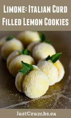 some lemon cookies are on a plate with mint sprigs in the middle and one is