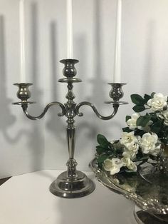 two silver candelabra with white flowers in the center