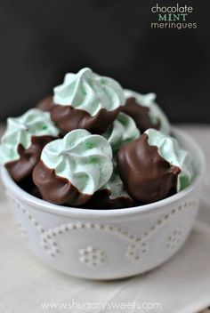 a white bowl filled with green and brown desserts sitting on top of a table