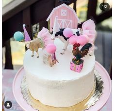 a white cake with pink frosting and small figurines sitting on top of it