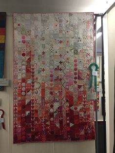 a red and white quilt hanging from the side of a wall next to a doorway