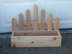 a wooden box sitting in front of a garage door with a picket fence on it