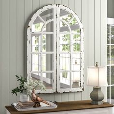 a mirror sitting on top of a dresser next to a lamp and vase with flowers