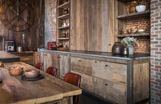 a wooden table sitting in front of a brick wall next to a counter with bowls on it