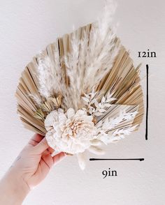 a person holding up a flower made out of old book pages with measurements on it