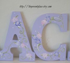 the letters are painted purple and have flowers on them, as if they were made out of wood