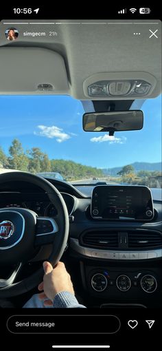 a person driving a car on the road with their hands on the steering wheel, while another person is taking a photo