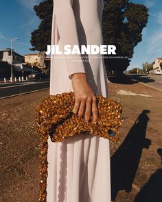 a woman in a white dress holding a gold sequin clutch on the cover of a magazine