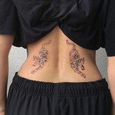 a woman with a tiger tattoo on her lower back is standing in front of a wall