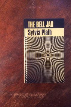 the bell jar by syivia plath on a wooden table with black and white lines