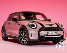 the front end of a white and black mini cooper hatchback parked on a pink background