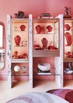 a room with pink walls and marble shelves filled with red jewelry on top of each shelf