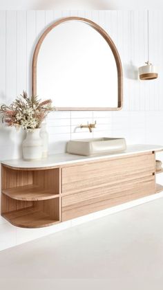 a bathroom with a sink, mirror and vase on the counter in front of it