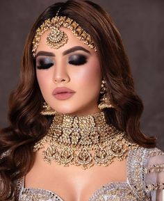 a woman wearing a gold and silver outfit with jewelry on her neck, shoulders and chest