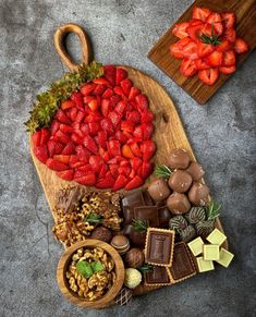 strawberries, chocolates and nuts arranged on a cutting board for a platter