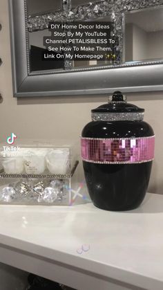 a black and pink vase sitting on top of a white table next to a mirror