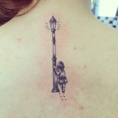 a woman with a tattoo on her back has a lamp post and is holding onto the pole