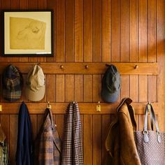 several hats and coats hanging on a wooden wall