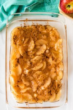 a casserole dish with apples and cinnamon in it on a white surface next to an apple