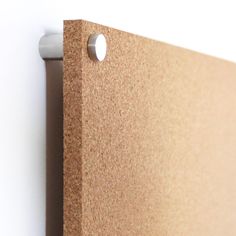 a close up of a cork board with holes in the middle and a white wall behind it