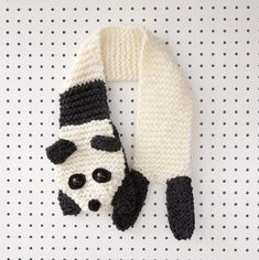 a knitted panda bear scarf hanging on a white polka dot wall with black and white dots