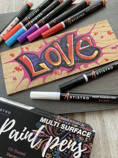 some crayons are sitting on top of a piece of paper with the word love painted on it