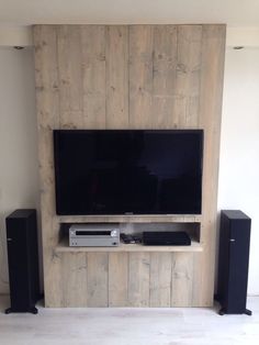 a flat screen tv sitting on top of a wooden wall next to speakers and an entertainment center