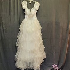 a white dress hanging on a wall next to flowers